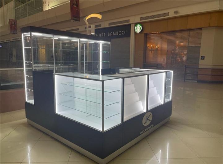 Isla de joyería con vitrinas iluminadas y torres de cristal en centro comercial