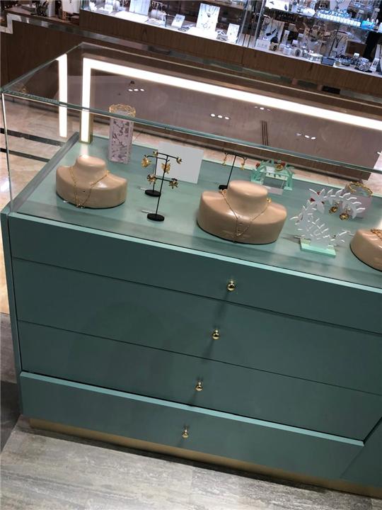 Vitrina de joyería con cajonera en color verde de marca y perfil dorado