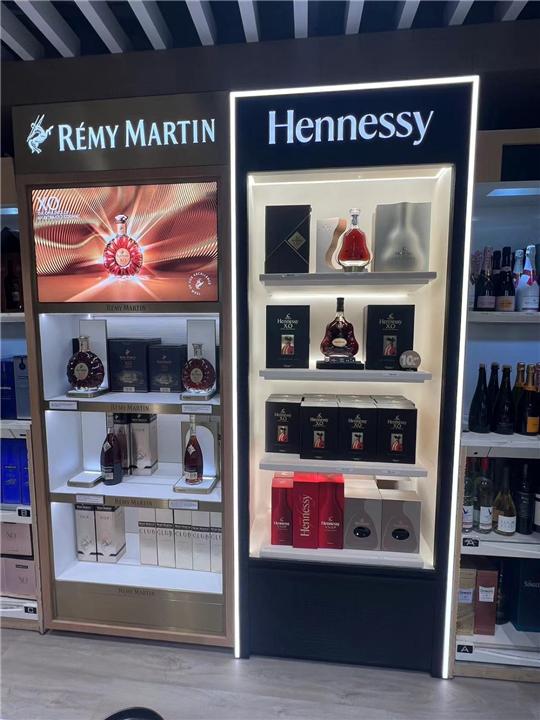 Muro de marca para coñac con caja de luz y repisas iluminadas en duty free