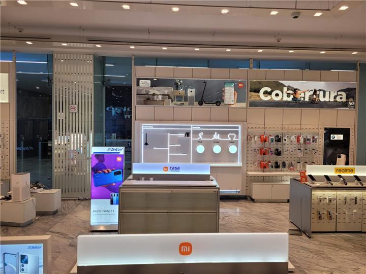 Tienda de tecnología con muros de accesorios y mostradores para smartphones